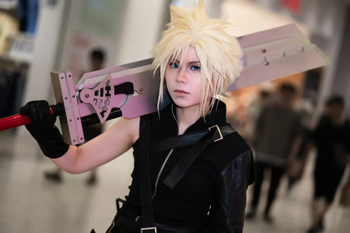 Person in detailed cosplay of famous video game character with big sword, indoors.