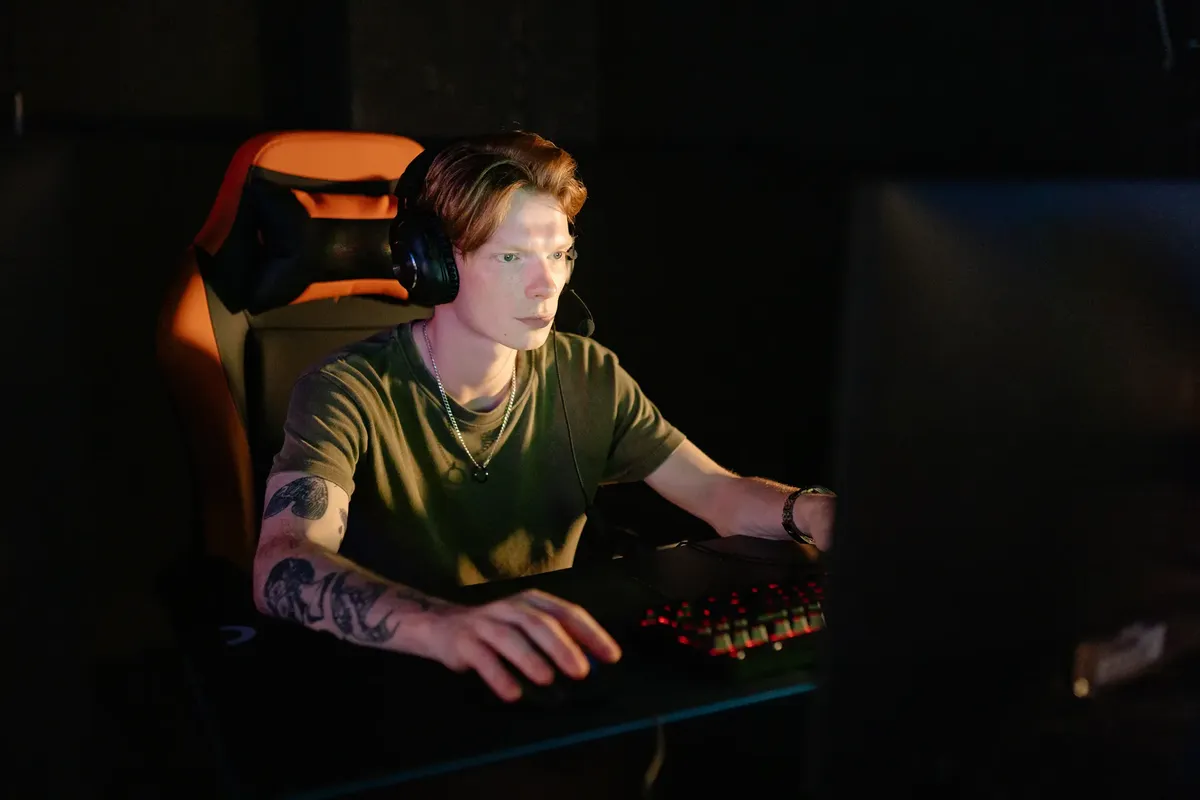若者がヘッドホンを装着してゲームチェアを使ってビデオゲームに没頭している。
