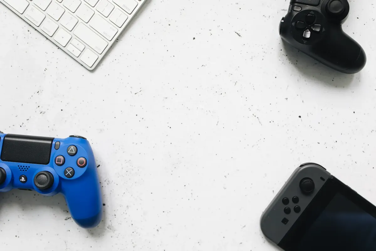 A variety of game controllers and a keyboard arranged on a white textured surface, offering a minimalist gaming setup.